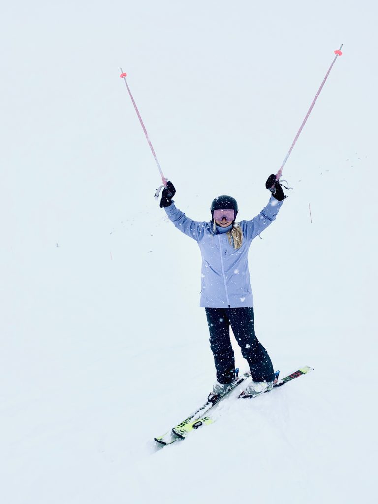 Frau mit Ski im Schneegestöber auf Piste